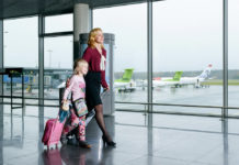 Взрослый сопровождает ребенка к выходу на посадку в самолет в аэропорту Рига