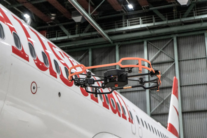 Дрон проводит инспекцию фюзеляжа самолета Austrian Airlines