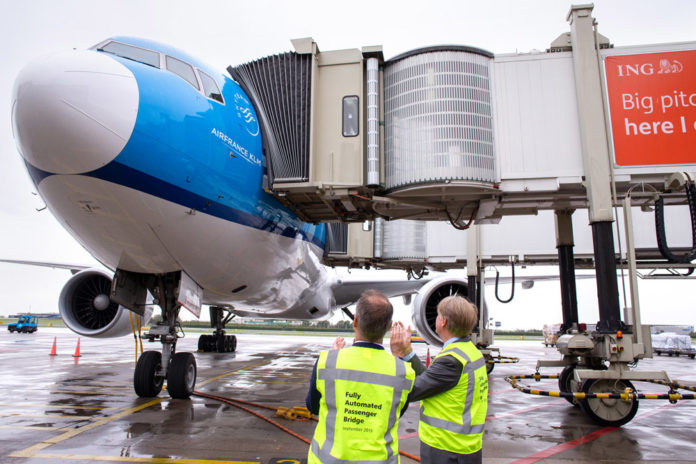 Автоматический сдвоенный телетрап присоединен к Boeing 777 KLM в аэропорту Амстердама Схипхол