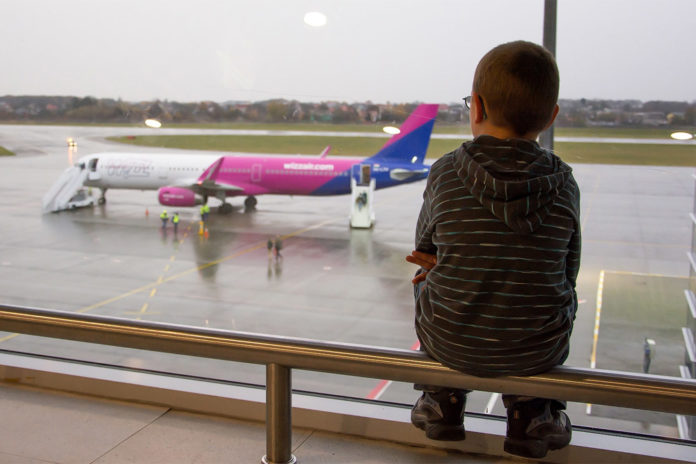Ребенок в аэропорту наблюдает за самолетом Wizz Air
