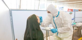 Медицинский работник берет мазок у пассажира для тестирования на коронавирус в аэропорту Вены Швехат