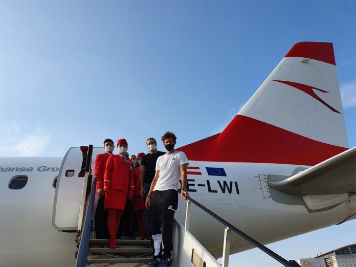 Пассажиры и бортпроводники Austrian Airlines в масках на трапе у самолета