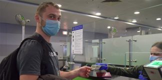 Пассажир в маске проходит паспортный контроль в аэропорту