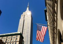 Флаг США на фоне небоскреба в Нью-Йорке