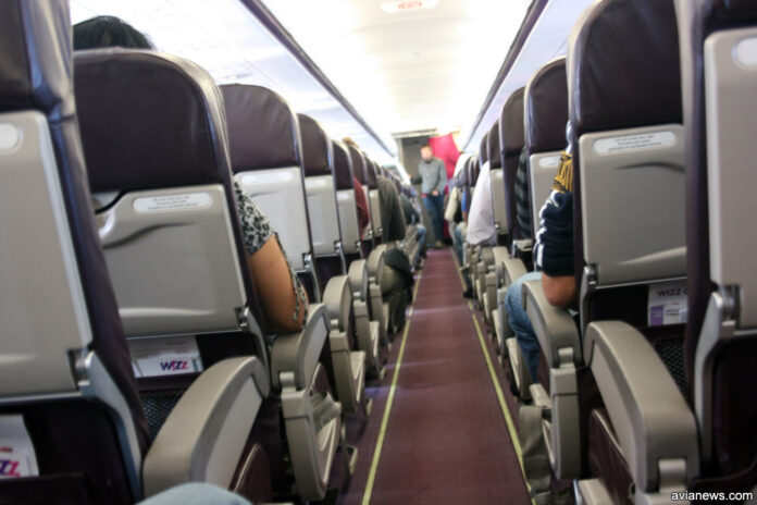 Пассажиры в салоне самолета. Вид из прохода самолета Пассажиры в салоне самолета. Вид из прохода самолета