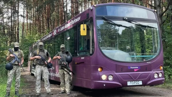 Украинские военные на фоне автобуса из Аэропорта Лутон